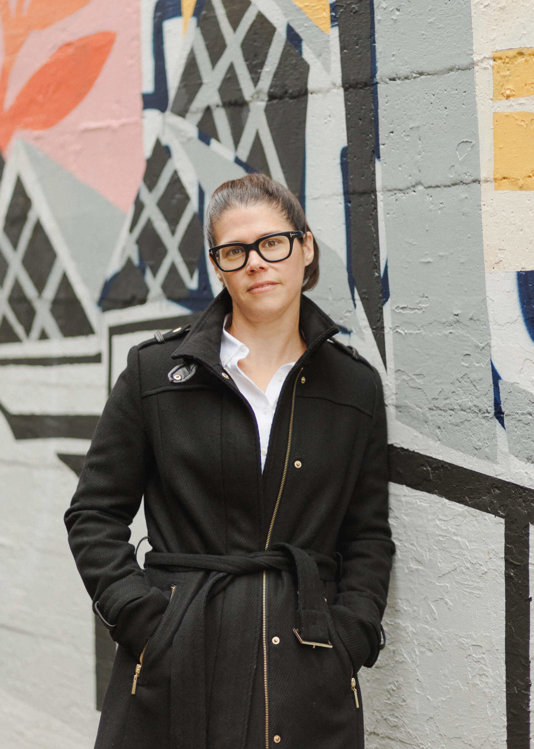 woman leaning against a wall with a brightly colored mural